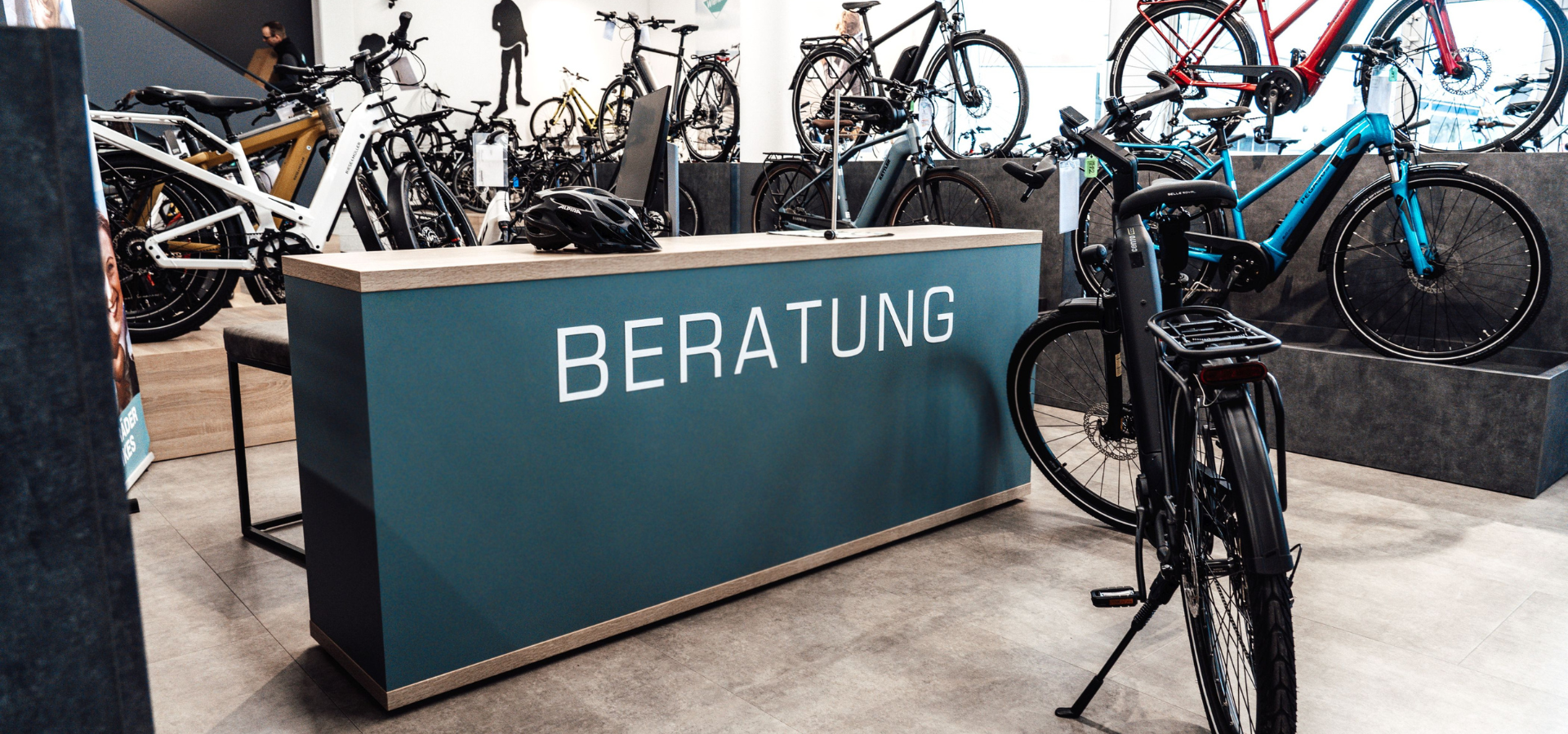 Neuer Verkaufsraum von Fahrrad Wierleuker mit großem türkisenen Beratungstresen und Fahrradpodesten nach der Umgestaltung durch Schemberg Ladenbau