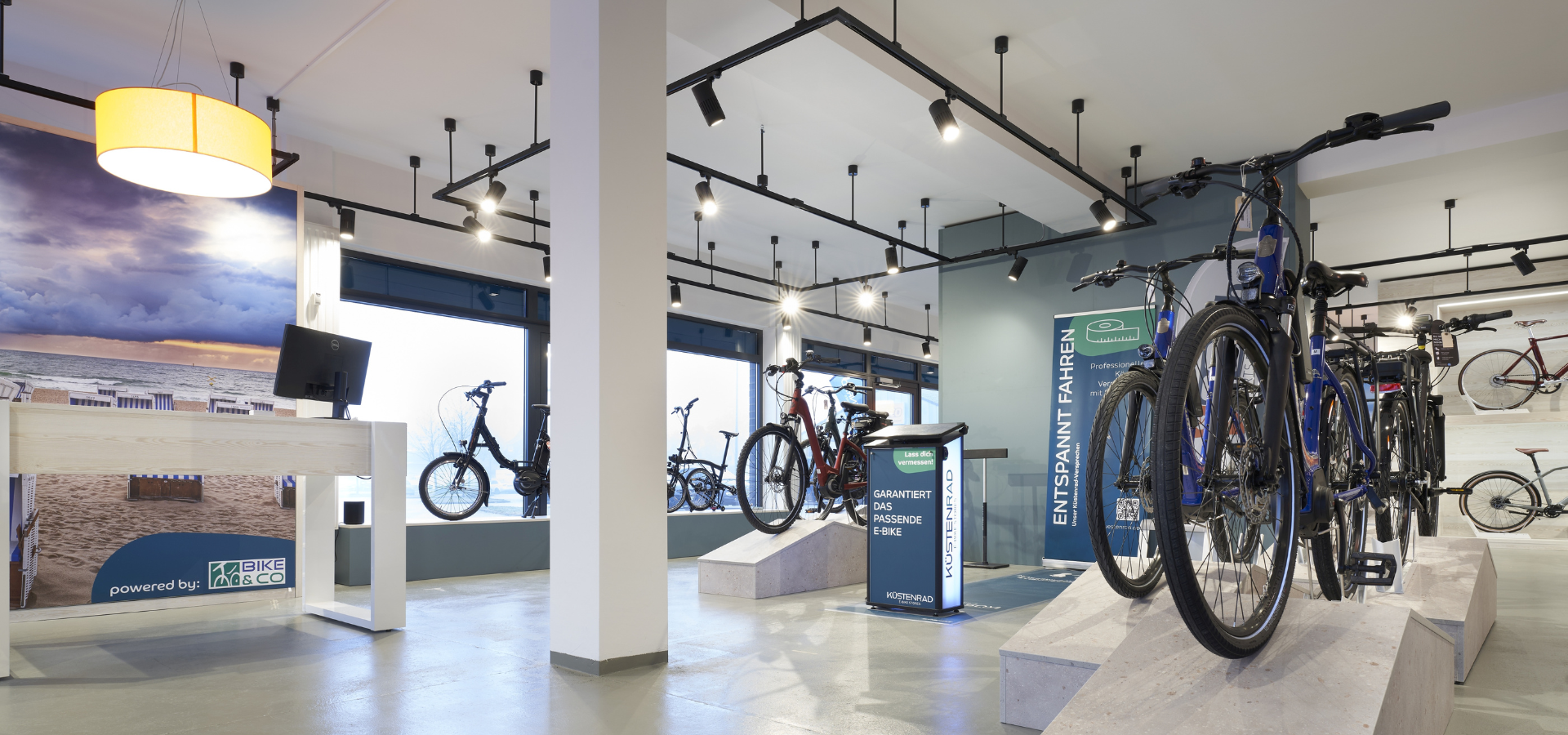 Neuer Verkaufsraum von Küstenrad in Pinneberg mit großformatigen Imagebildern und Podesten für Fahrräder nach der Umgestaltung durch Schemberg Ladenbau