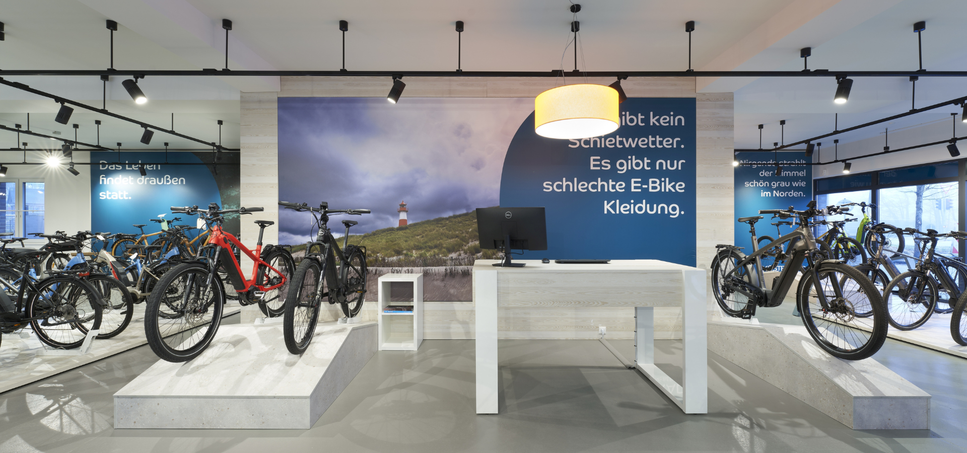 Neuer Verkaufsraum von Küstenrad in Pinneberg mit großformatigen Imagebildern und Podesten für Fahrräder nach der Umgestaltung durch Schemberg Ladenbau