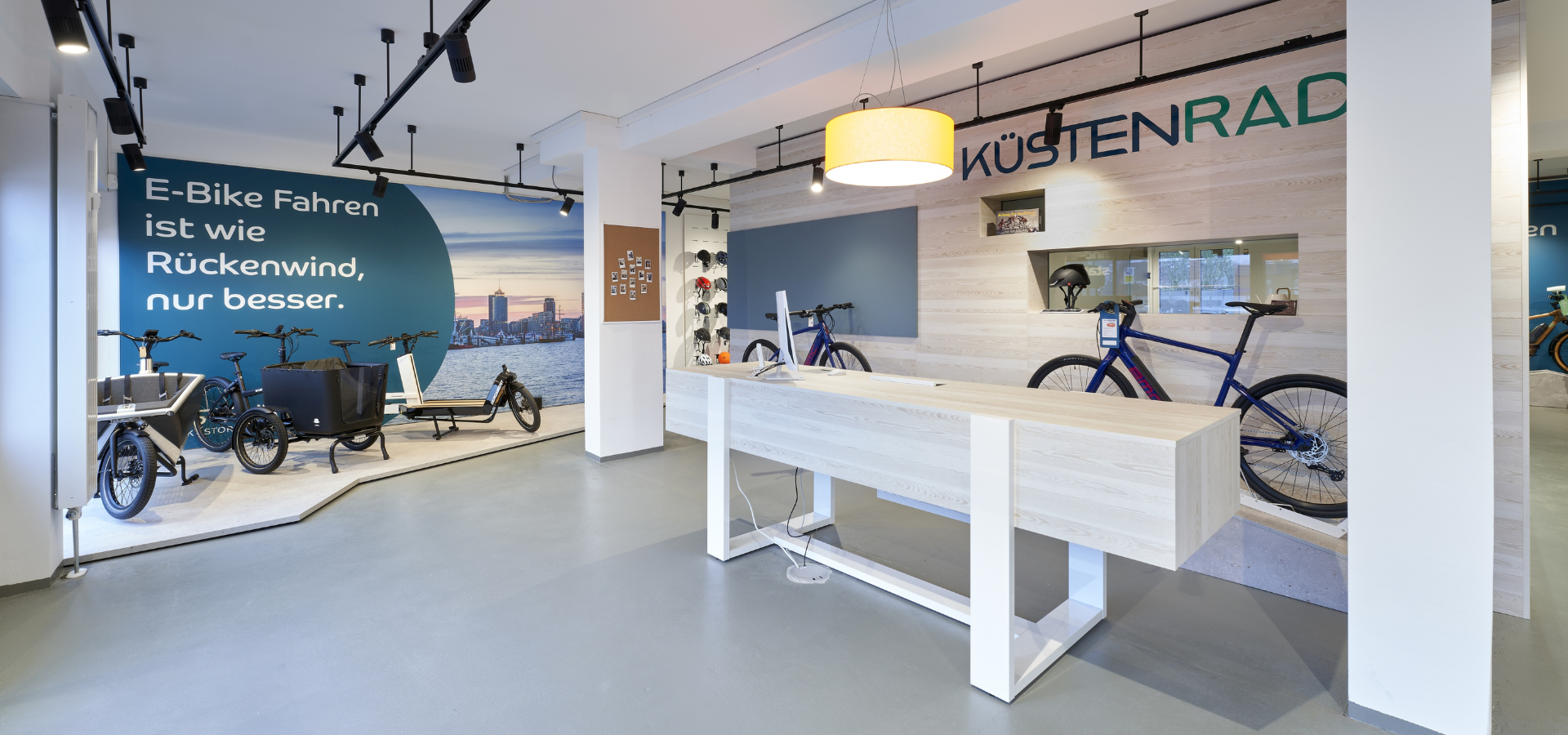 Neuer Verkaufsraum von Küstenrad in Pinneberg mit großformatigen Imagebildern und Podesten für Fahrräder nach der Umgestaltung durch Schemberg Ladenbau