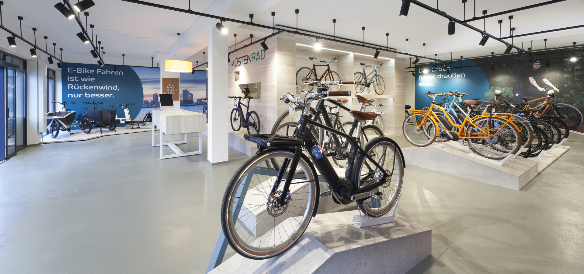 Neuer Verkaufsraum von Küstenrad in Pinneberg mit großformatigen Imagebildern und Podesten für Fahrräder nach der Umgestaltung durch Schemberg Ladenbau
